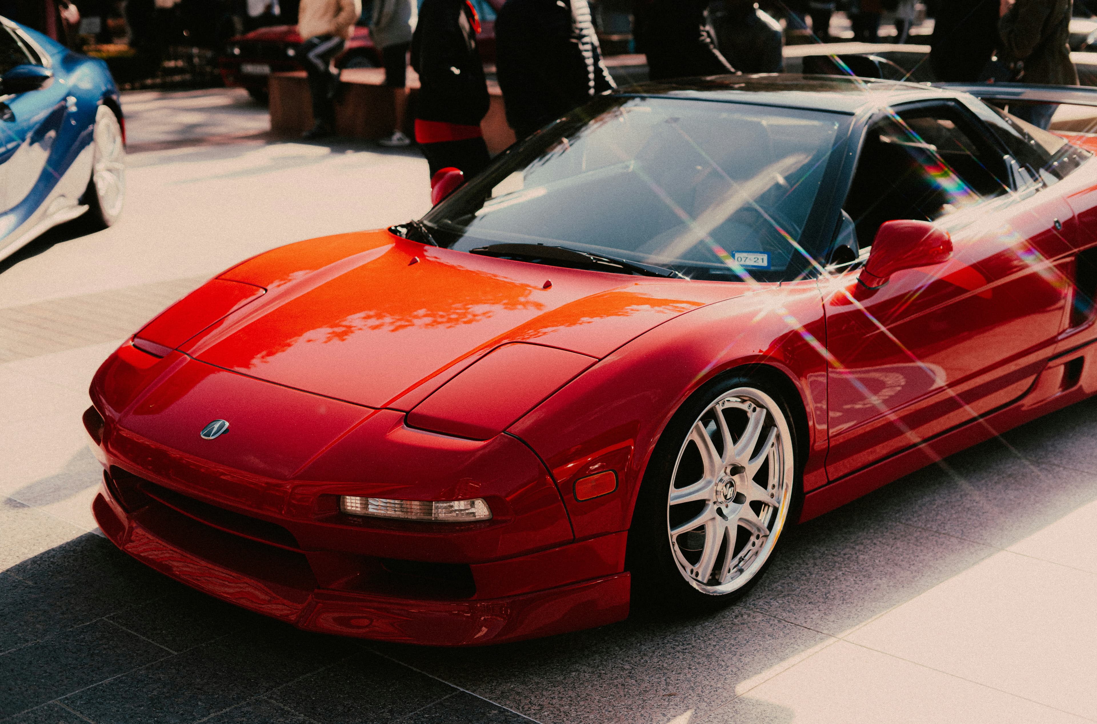 Red Honda NSX NA1 from an elevated front-three-quarter angle, showing its low nose, windshield and sculpted side bodywork